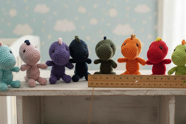 Row of colorful crochet toys with a ruler for scale against a light blue wall with cloud patterns.