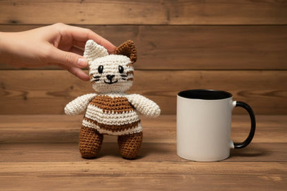 Handmade crochet cat toy next to a white mug on a wooden surface