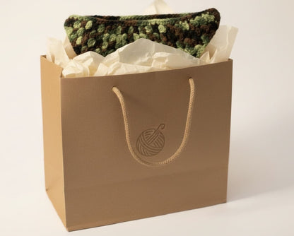 Brown paper bag with a crochet item on a white background