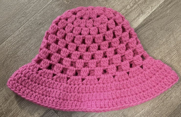 Pink crochet hat on a wooden surface