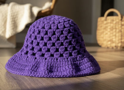 Purple crocheted hat on a wooden surface with a blurred background