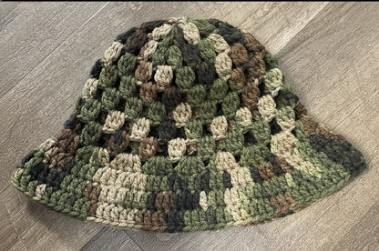 Camouflage-patterned crochet hat on a wooden surface
