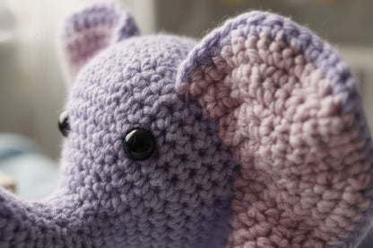 Close-up of a purple crochet elephant with pink ear