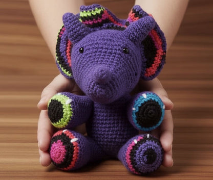 Purple crochet dinosaur toy held in hands on a wooden surface
