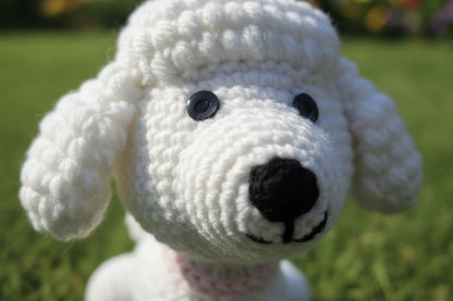 White crocheted dog toy with black eyes and nose on a grassy background