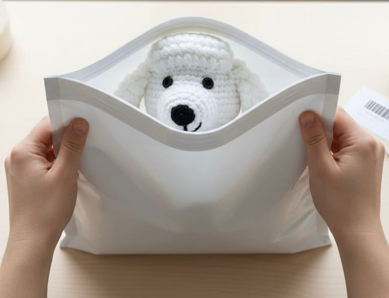 Small white crocheted dog toy peeking out from a white envelope held by hands.