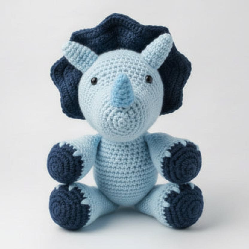 Crocheted blue and navy dinosaur toy on a white background