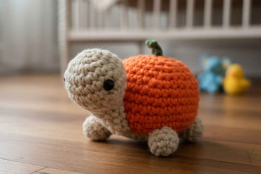 Crocheted turtle with orange shell on a wooden floor