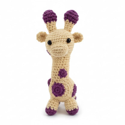 Crocheted giraffe toy on a crib with baby blocks and a pacifier.