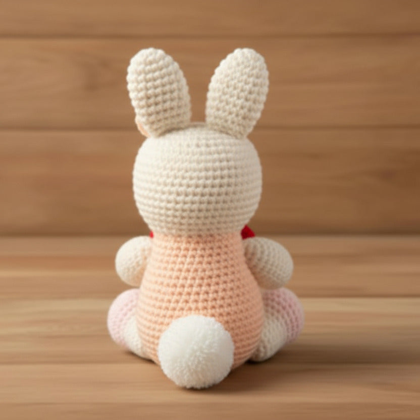 Crocheted bunny toy on a wooden surface with a wooden background