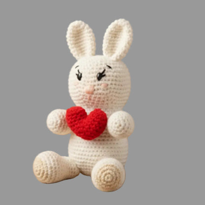 Crocheted bunny toy with a red heart on a gray background